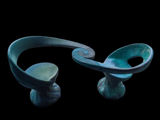 The Unity Chairs. Cast bronze, 36 inches high x 5.5 ft long x 24 inches wide. Page In the Sun Café, Puerto Vallarta, Mexico. With two different colors or the same colors, the two interlocking bronze chairs compel people to sit facing each other, encouraging companionship.